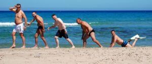 Męska część załogi rejsu ustawiona na plaży w Tunezji ustawieni jak na obrazach przedstawiających ewoluję homo sapiens