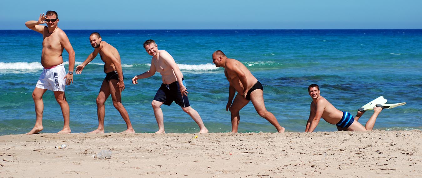 Męska część załogi rejsu ustawiona na plaży w Tunezji ustawieni jak na obrazach przedstawiających ewoluję homo sapiens 