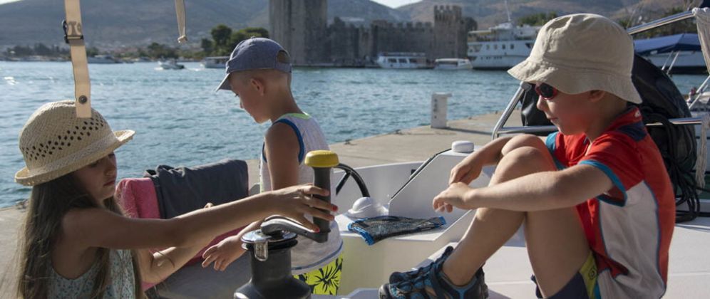 młodzi załoganci kręcą kabestan wyczarterowanego katamaranu w porcie Trogir w Chorwacji