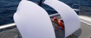 rejs katamaranem w Czarnogórze. relaks matki z dzieckiem na siatce z przodu jachtu pod słoneczną osłoną z prześcieradeł
