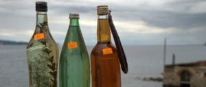 trzy butelki domowej produkcji chorwackiego alkoholu sprzedawane przez ulicznego sprzedawcę na ulicy portowej na wyspie Vis