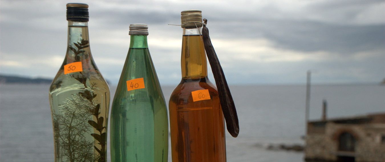 trzy butelki domowej produkcji chorwackiego alkoholu sprzedawane przez ulicznego sprzedawcę na ulicy portowej na wyspie Vis. Kasa jachtowa