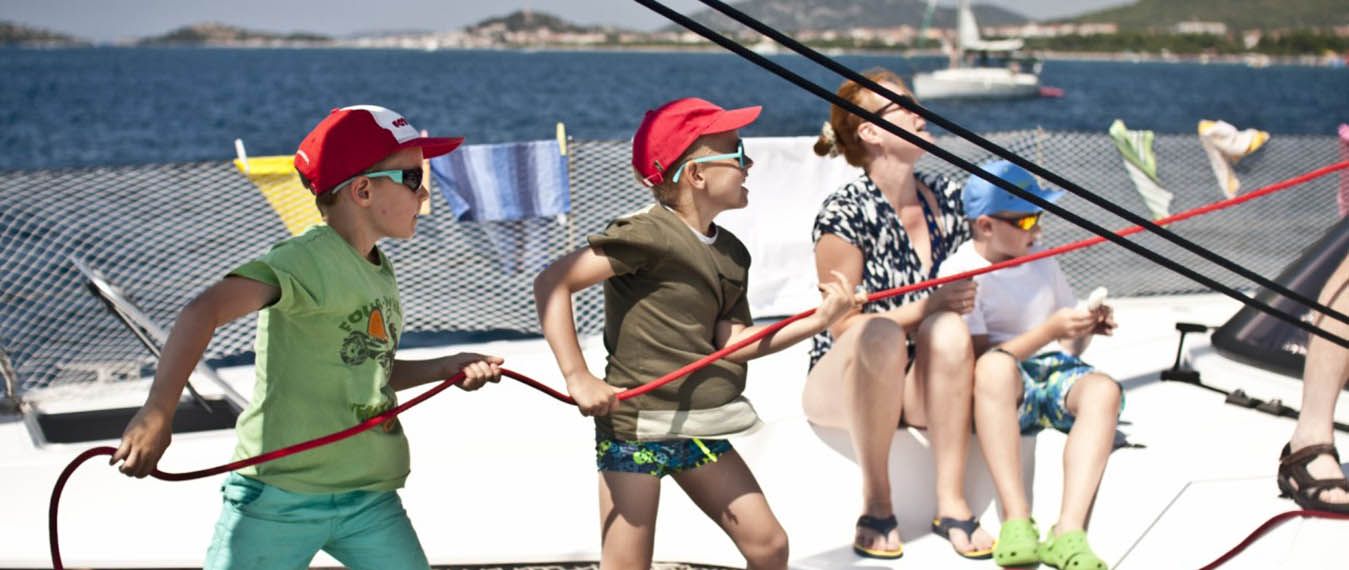 dzieci wcielają się w załogę katamaranu ciągnąc za linę. Rejs w Chorwacji