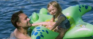 dziecko na dmuchanej zabawce do zabawy w wodzie. Rejs rodzinny katamaranem. Włochy.